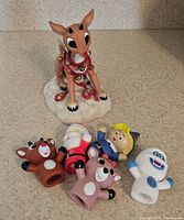 Photo showing Rudolph sitting on snow base with red nose and five finger puppets of Island of Misfit Toys characters.