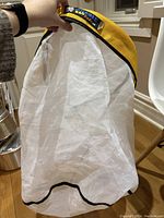 Hand holding the white fine mesh wash bag showing the full height and mesh material, black bottom edge visible.