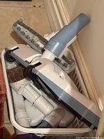 Various Electrolux vacuum attachments in white and grey, showing floor brush and other cleaning tools with bristles and brushes.