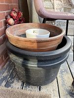 Three plant pots stacked: an extra large clay pot on top of a large black plastic pot, with a small white pot inside the clay pot.