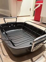 Angled side view showing the non-stick pan with metal handles and the metal roasting rack inside it.