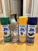 Four Rust-Oleum spray paint cans arranged on floor showing different finishes and nearly full condition.
