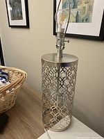 Full view of the cylindrical metal lamp base with Art Deco pattern, metal top with bulb socket, and power cord visible.