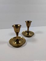 Single brass candlestick holder shown from an angle on white background highlighting size and condition.