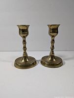Pair of vintage brass candlestick holders side by side on a white background.