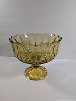 Front view of the amber glass pedestal bowl showing scalloped rim and textured design