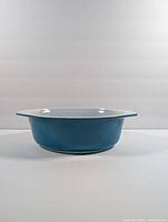 Side view of blue Pyrex casserole dish showcasing its height and wide handles.
