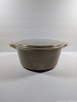 Front view of vintage Pyrex speckled beige casserole dish with lid showing the full body and handles.