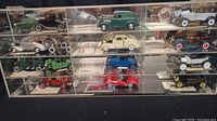 Wide shot of multiple rows of model cars in clear acrylic compartments showing variety of colors and styles.