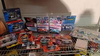 Overview photo of lots of die-cast cars including Speed Wheels, Looney Tunes, M2 Machines, two Hot Wheels 1:18 scale motorcycles, and sports cards on a metal shelf