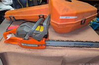 Full side view of orange Husqvarna 41 chainsaw with bar attached and matching carrying case in background
