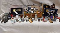 Full overview of the lot showing an Elvis Presley watch in case, multiple lighters, keychains, knives, and collectibles arranged on white fabric.