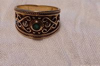 Front view of wide gold band showing emerald and diamond accents