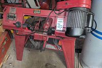 Full view of the horizontal and vertical metal cutting band saw showing red frame, motor and blade area.