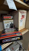 Three boxed items on shelf: B&M Launch Control, Comp Cams vacuum canister and PowerBleeder pressure bleeder