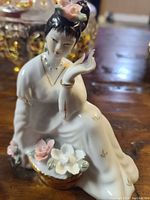 Close-up of one hand-painted porcelain Geisha figurine showing flowers and gold trim details