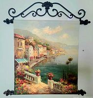 Full view of oil painting with coastal village scene and wrought iron decorative frame