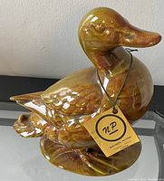 Front and side view of ceramic duck showing glossy finish, detailed feathers, and original Northern Pottery tag attached to neck.