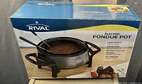 Box of Rival Electric Fondue Pot showing product image and details including 3 quart capacity, four fondue forks, non-stick surface, and full immersion for easy cleaning.