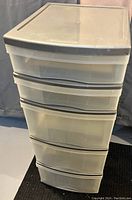 Front angled view of the five drawer organizer showing all drawers closed with semi-transparent fronts and beige frame.