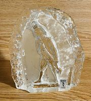 Clear glass block figurine with textured edges and a detailed human figure inside, shown from the front on a wooden surface.