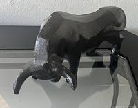 Black cast iron bull sculpture showing front and top details including horns and muscular body
