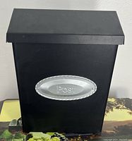 Front view of black metal mailbox with silver 'Post' emblem on front.