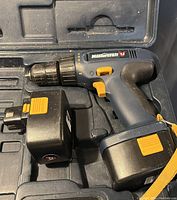Mastercraft cordless drill with one battery inserted, showing blue and black body with yellow trigger and chuck control, resting inside the carrying case.