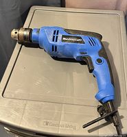 Full view of the Mastercraft blue hammer drill showing the chuck and auxiliary handle.