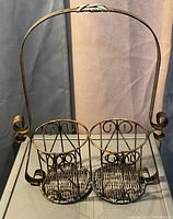 Single photo of a brown metal condiment holder showing two circular compartments and an arched handle with scroll details.