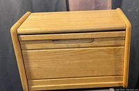 Front view of solid wood bread box with closed door showing carved handle groove.