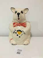 Front view of vintage ceramic bear cookie jar with red bow tie, holding a cookie, standing upright.