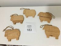 Five wooden animal ornaments laid flat on table, each with attached hanging twine loops. Front and back views from slightly different angles.