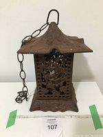 Front angle of cast iron pagoda lantern showing roof, chain, and base with decorative cut outs