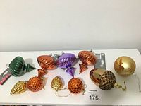 All 10 ornaments of varied shapes and warm metallic colors displayed on a white surface.