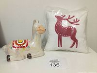Both small Christmas pillow and ceramic sparkly llama piggy bank displayed together