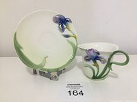 Front view of 3D iris cup and matching saucer showing flower detail and handle shape.