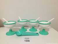 Four green and white vintage ice cream cups displayed with four white spoons and one green scoop placed in front.