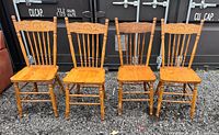 Four solid wood chairs in a row showing their full front view and intricate carving on the backrest.