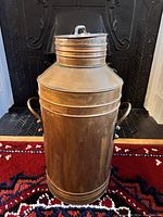 Front view of the antique copper milk can showing body, handle, and lid.