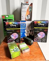 Overview of the lot showing multiple boxed Christmas lighting products from Disney, Holiday Joy, Sylvania and NOMA, and a few smaller light bulb packages