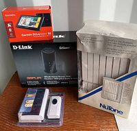 Full view of all items in lot showing Garmin GPS, D-Link router, Graviti wired doorbell, and NuTone air filter boxed