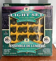 Front view of the original box containing the John Deere 20-piece decorative light set depicting tractor shapes, labeled as special edition and suitable for indoor and outdoor use.