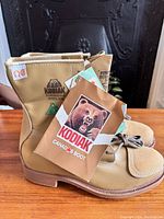 Close-up of new Kodiak insulated steel toe boots in tan leather showing tags and detailed logos.