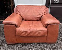 Front view of the large brown leather armchair showing seat, backrest, and armrests.
