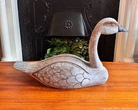 Side view showing detailed feather carvings and painted features of the large wooden goose decoy.