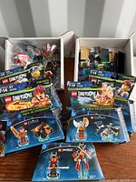 Six LEGO Dimensions Fun Packs with damage to packaging, featuring characters from Chima, Ninjago, and The Lego Movie, along with loose LEGO pieces