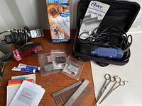 Overview photo of all tools in the pet grooming lot including clippers, blades, scissors, combs, nail care tool, and manuals.