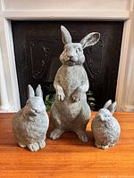 Front view of three bunny rabbit statues in a row, showing size variation and realistic texture.