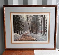 Framed print of winter landscape by Frank Panabaker showing snowy woods and path, in wood frame with double mat.